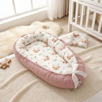Réducteur de lit bébé cocon sécurisant rose posé au sol